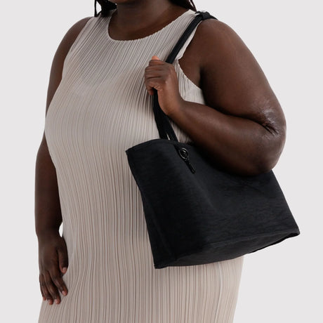 Black nylon medium tote bag held on a shoulder with wide strap handles