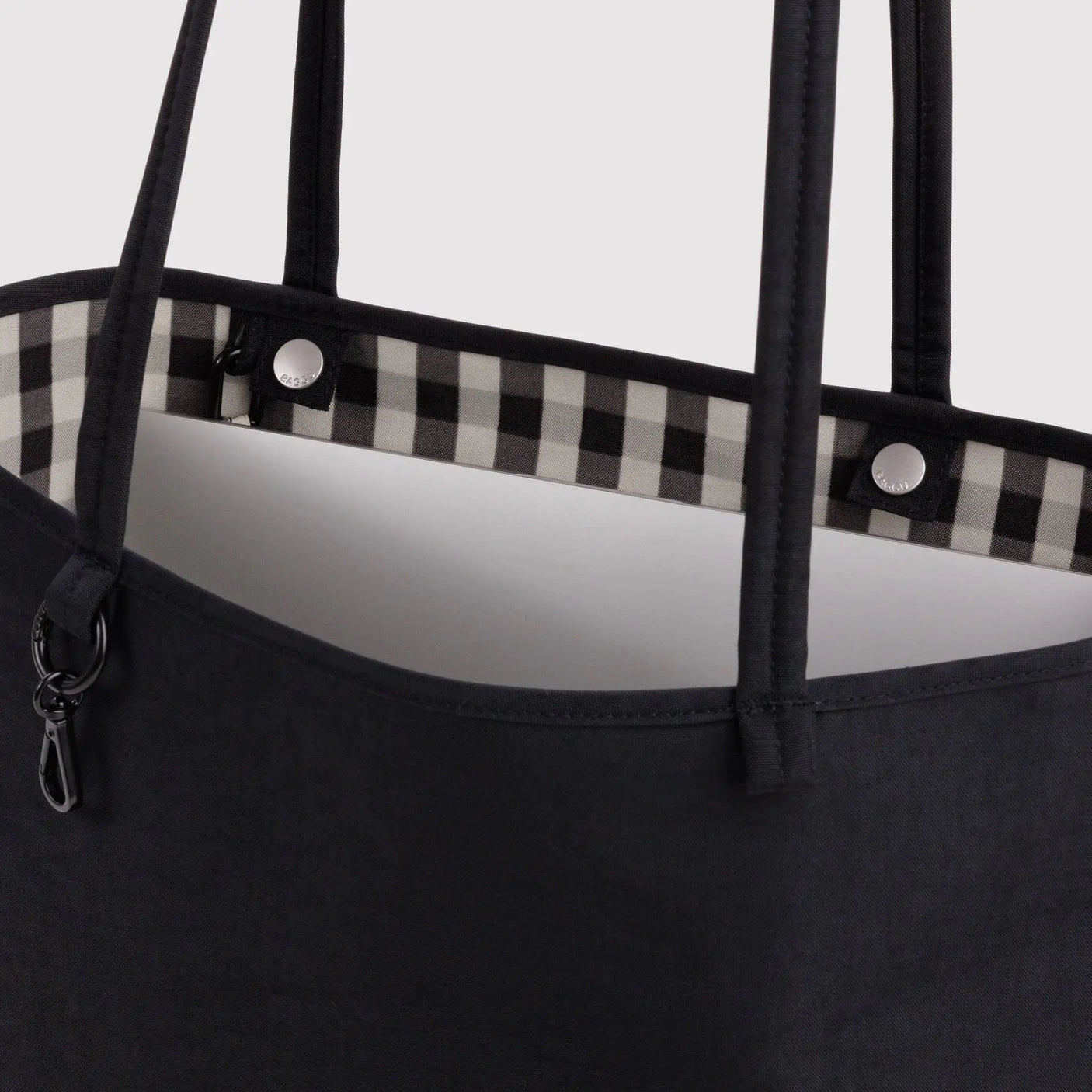 Medium reversible nylon tote in dark black with gingham lining, top handles and zip pocket
