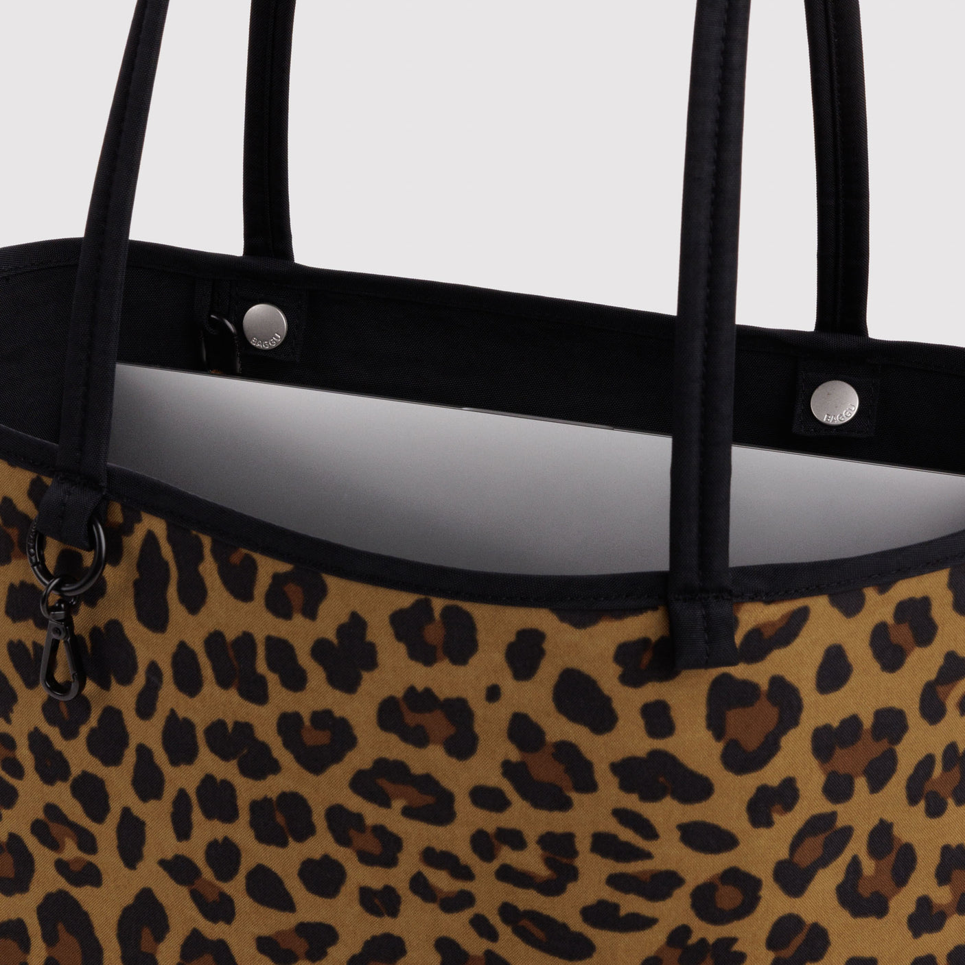 Close-up of leopard print reversible tote with black handles and metal snaps