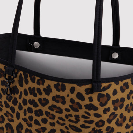 Close-up of leopard print reversible tote with black handles and metal snaps