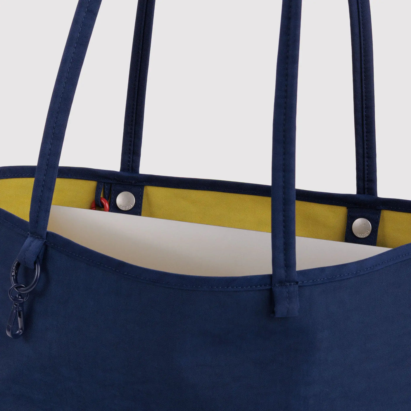 Navy nylon tote bag with yellow reversible lining and two top handles, snap pocket