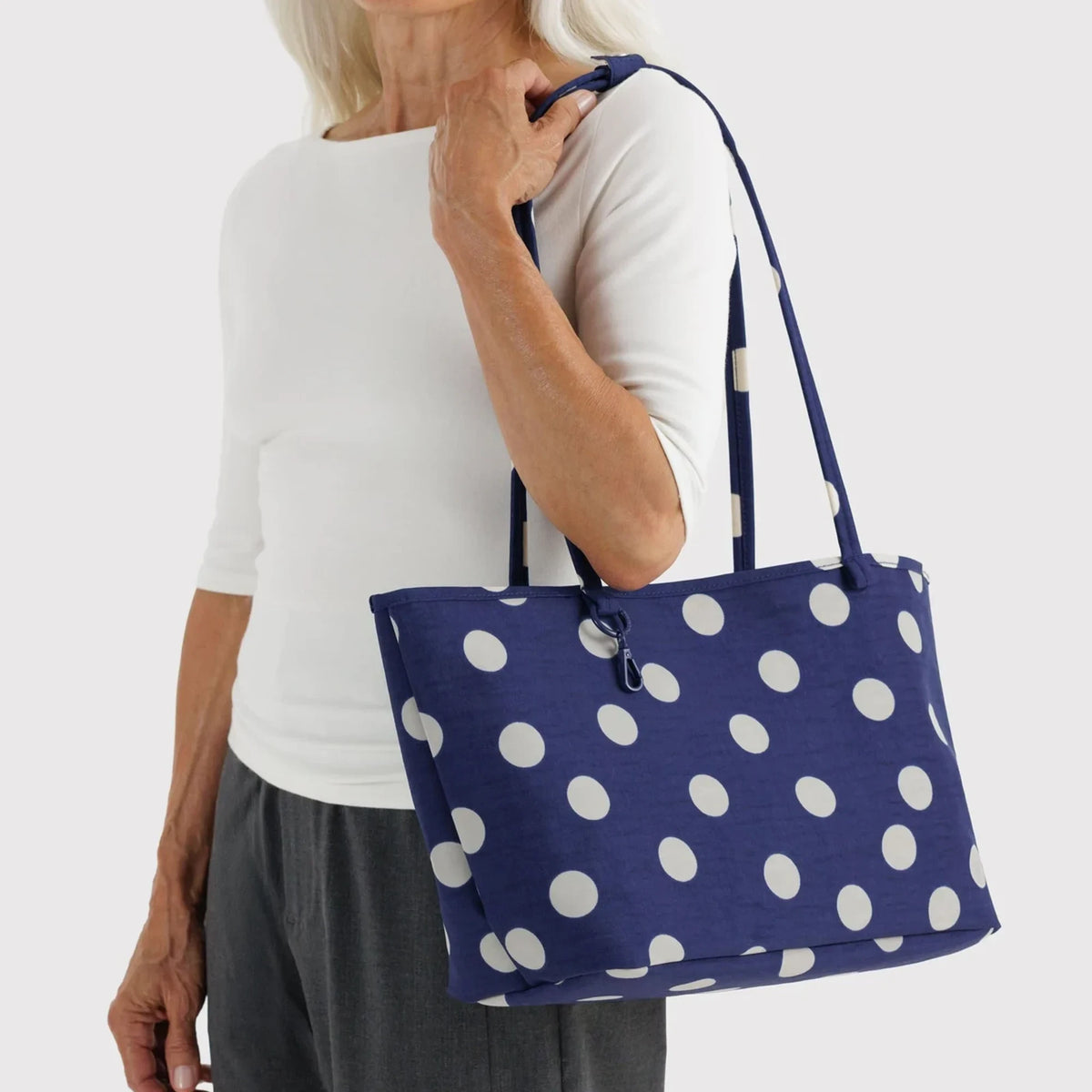 Reversible nylon tote worn, navy polka-dot exterior with short handles