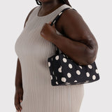 Black nylon bowler bag with cream polka dots, held by model.