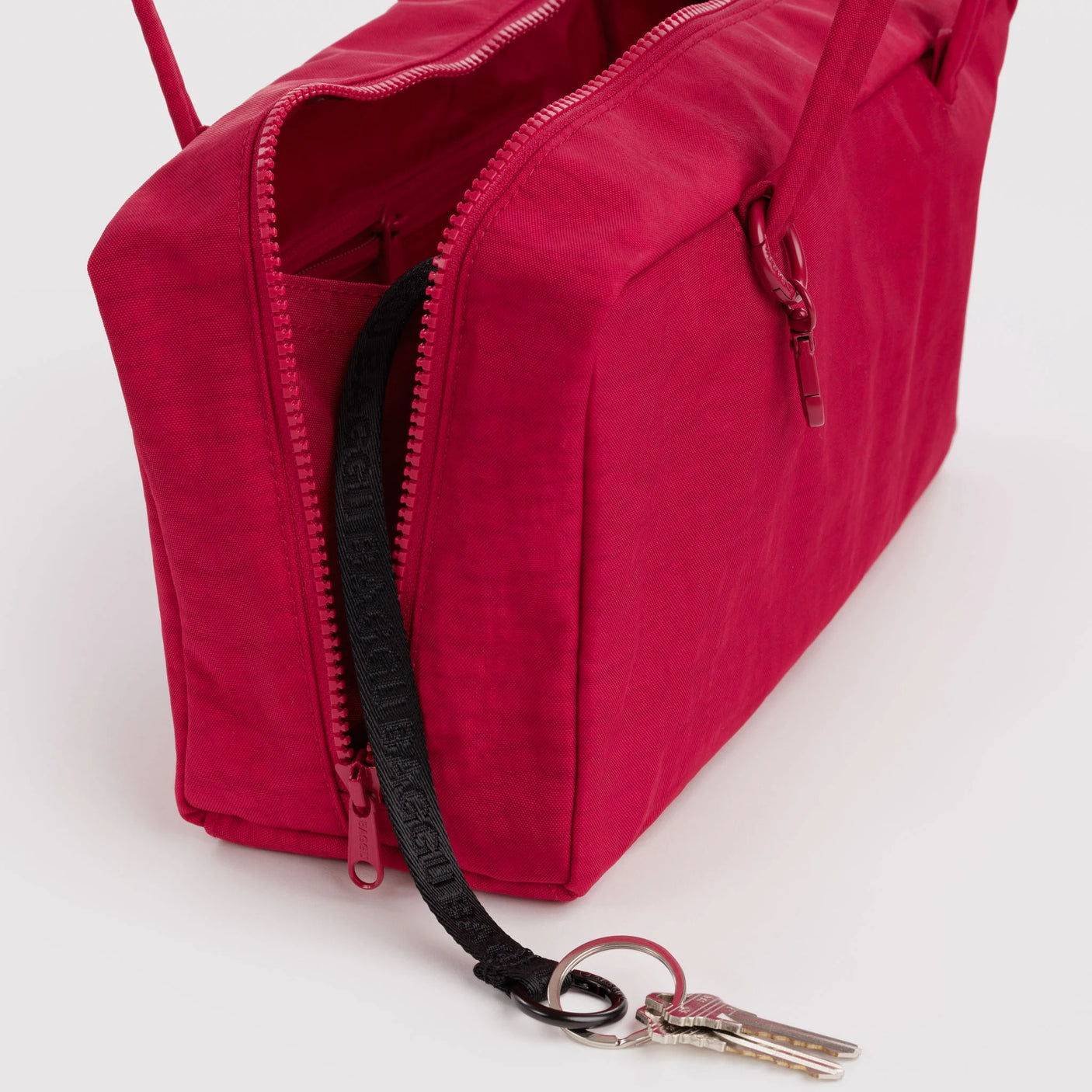 Cherry red nylon bowler bag close-up: zippered opening and metal key clip