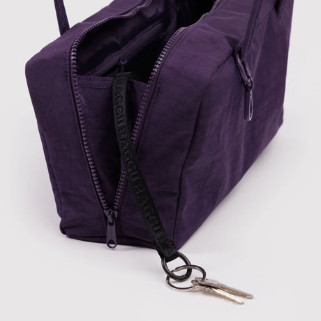 Deep purple rectangular fabric bag with double zipper compartments and black key strap holding two silver keys