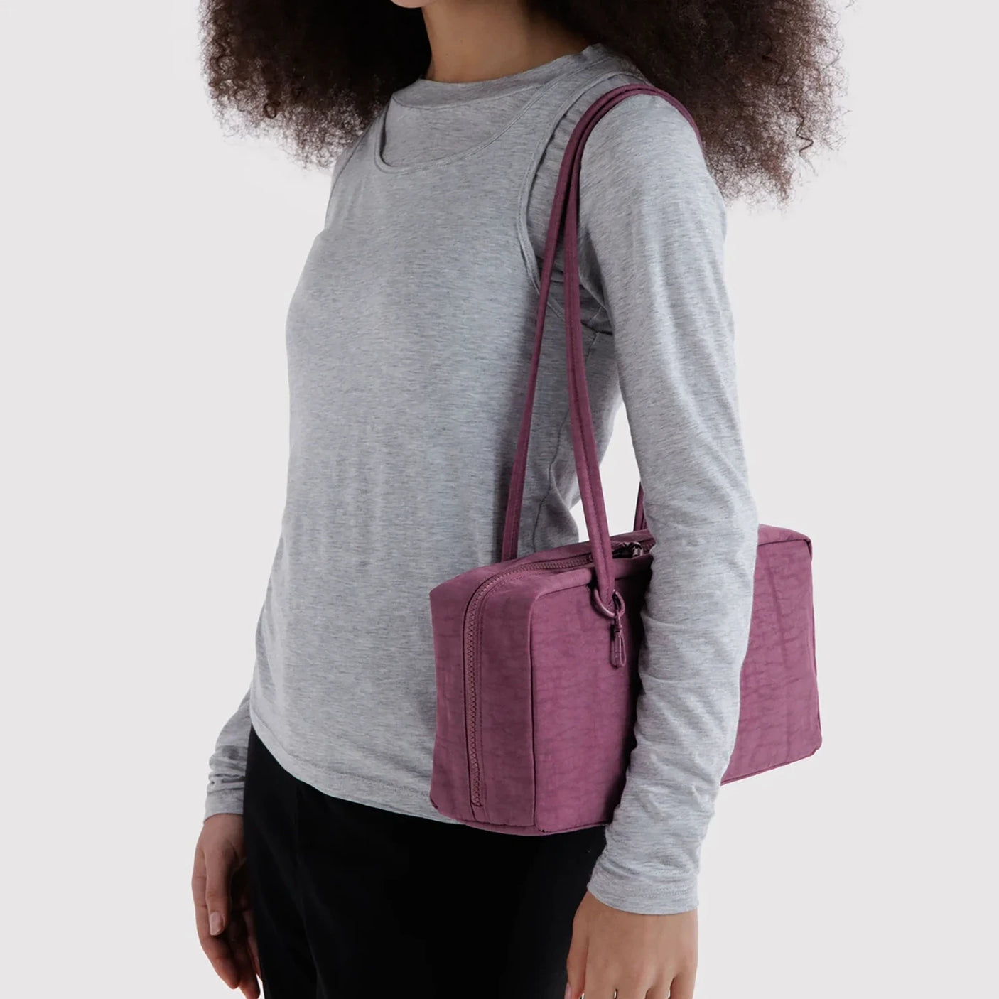 Plum nylon bowler bag worn on shoulder, zippered front and handles visible