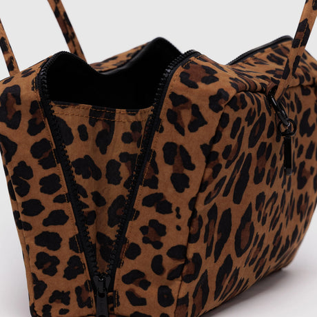 Leopard print nylon bowler bag with partially open zipper showing black interior and long straps on gray background