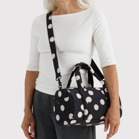 Polka-dot nylon duffle bag worn crossbody, black handles and adjustable strap