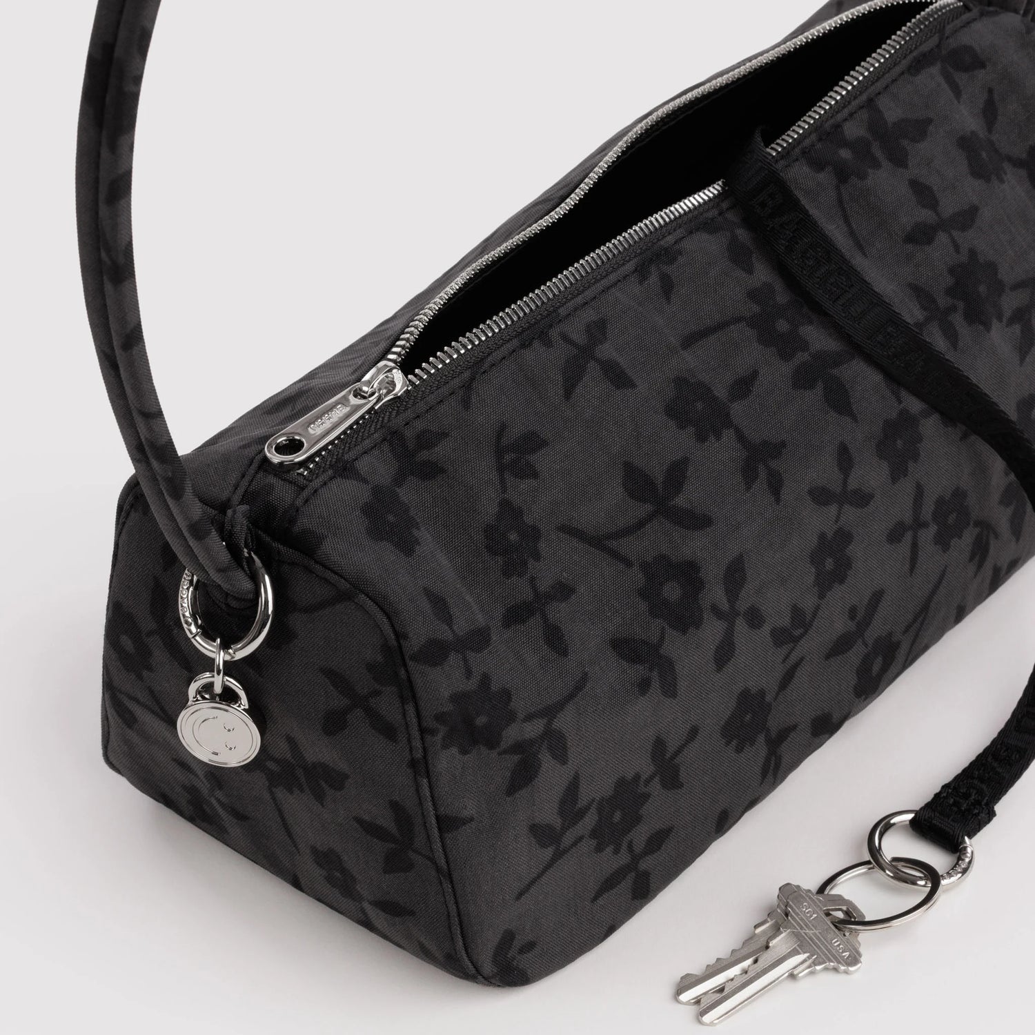 Charcoal nylon bag detail: floral print, metal zipper, key fob on ring