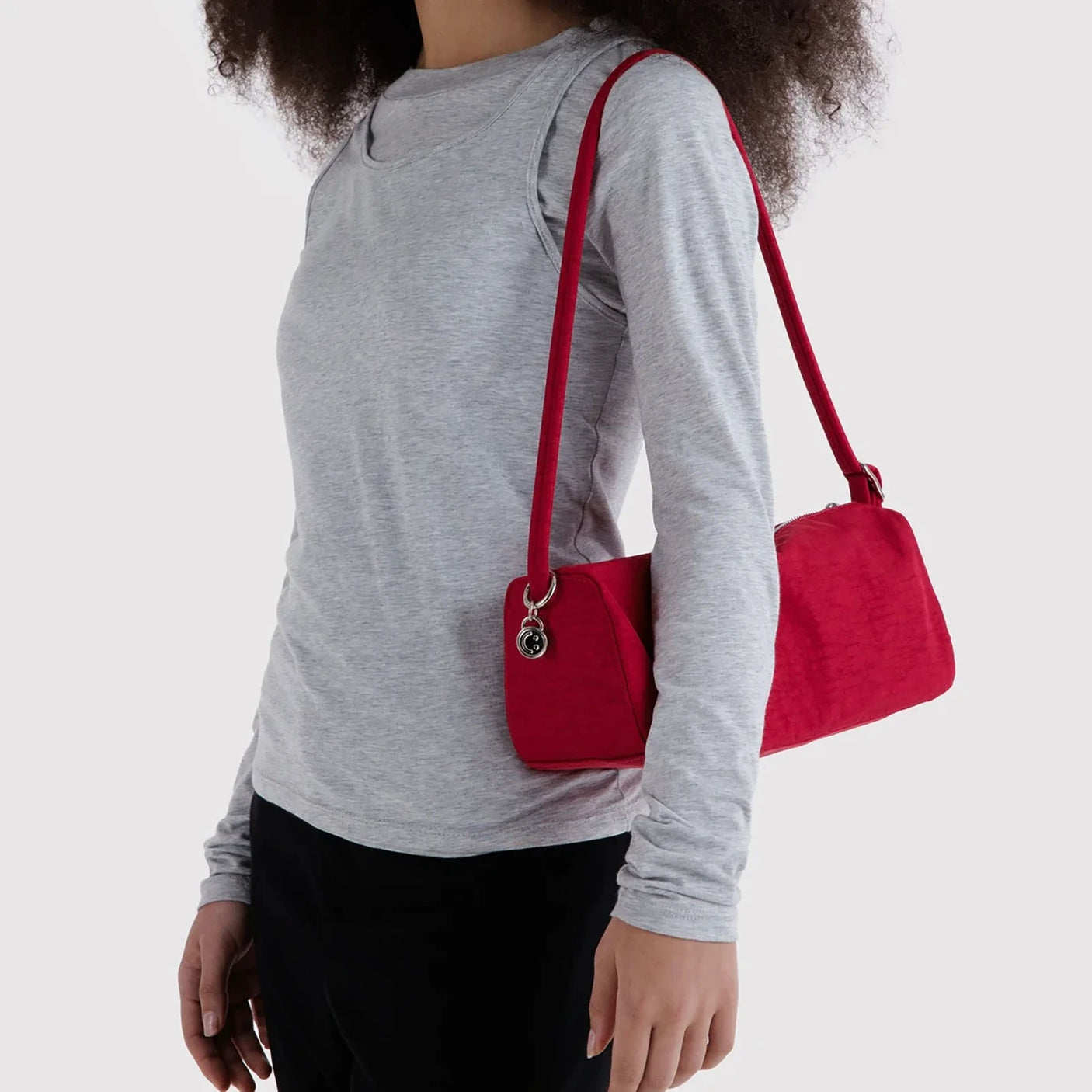 Cherry red nylon crossbody bag with zip top, worn over the shoulder