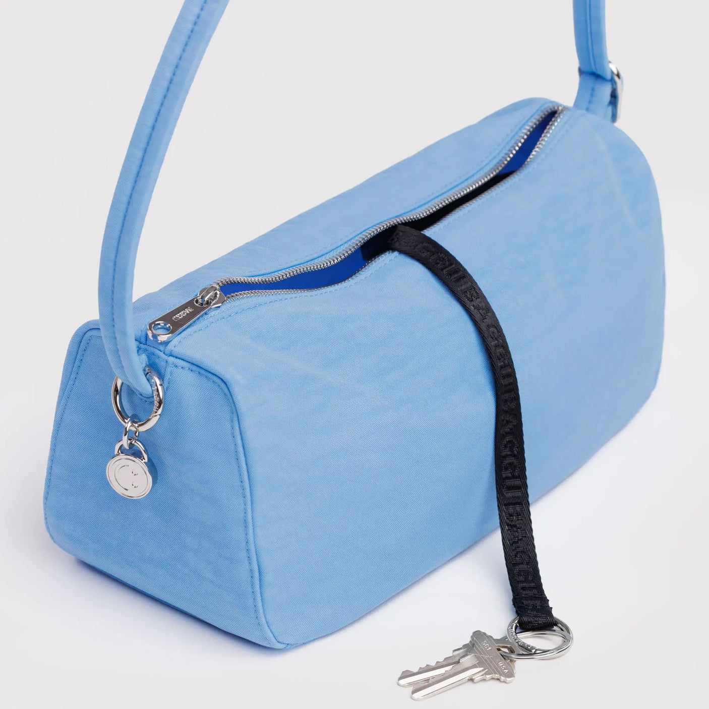 Baggu nylon loaf bag in light blue, zip top with black strap and keyring key holder