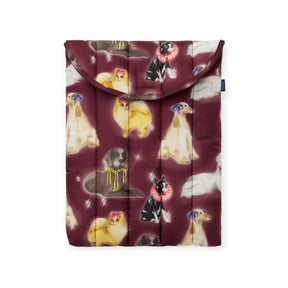 The Baggu Puffy Laptop Sleeve 13"/14" - Fancy Dogs features a padded maroon case with illustrations of various dog breeds, some wearing bows, on a white background.