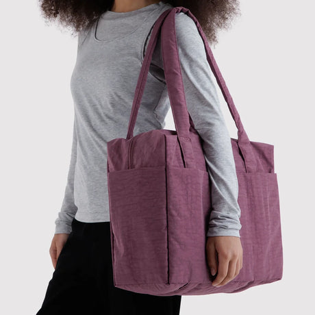 Plum zip-top tote bag with two handles and front pockets, carried over shoulder