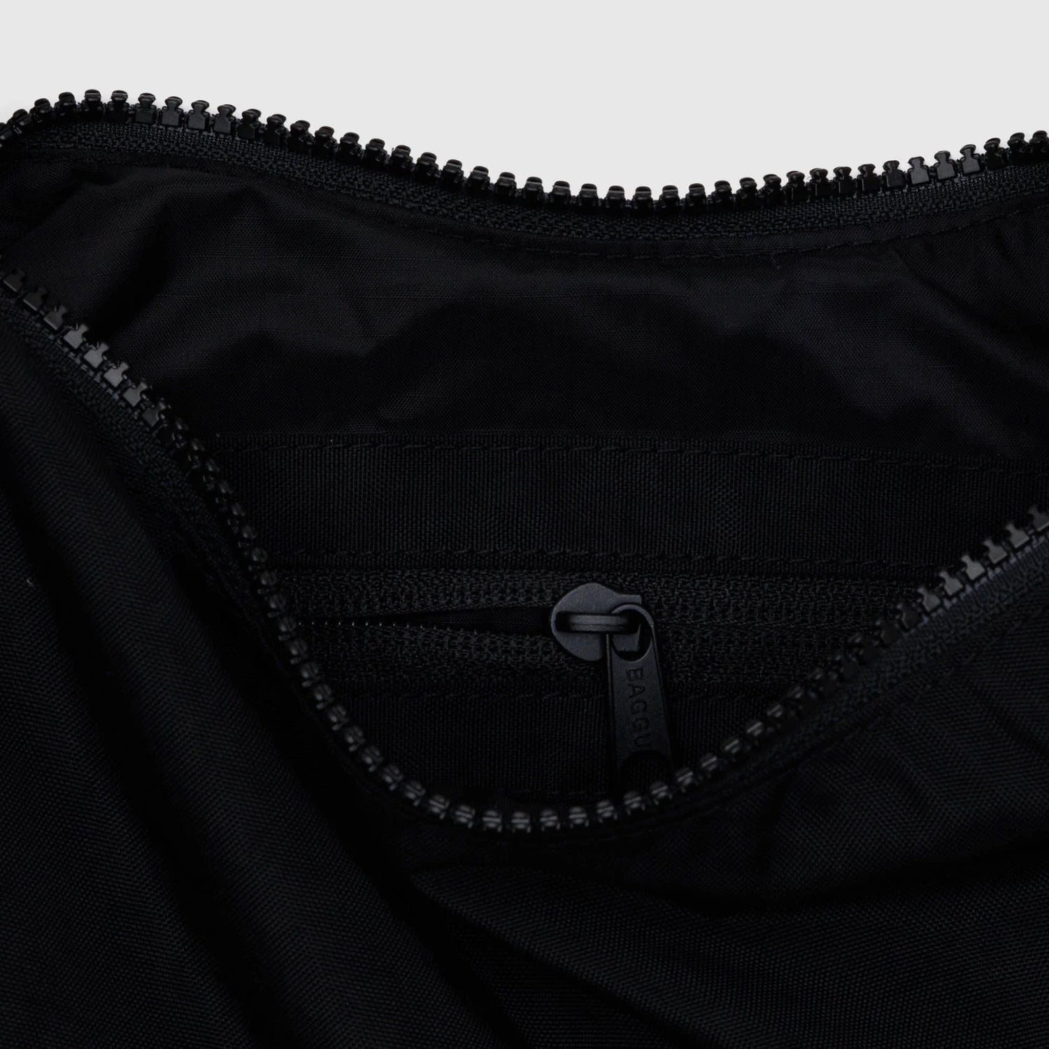 Black nylon crescent bag interior with zipper and stitched logo patch