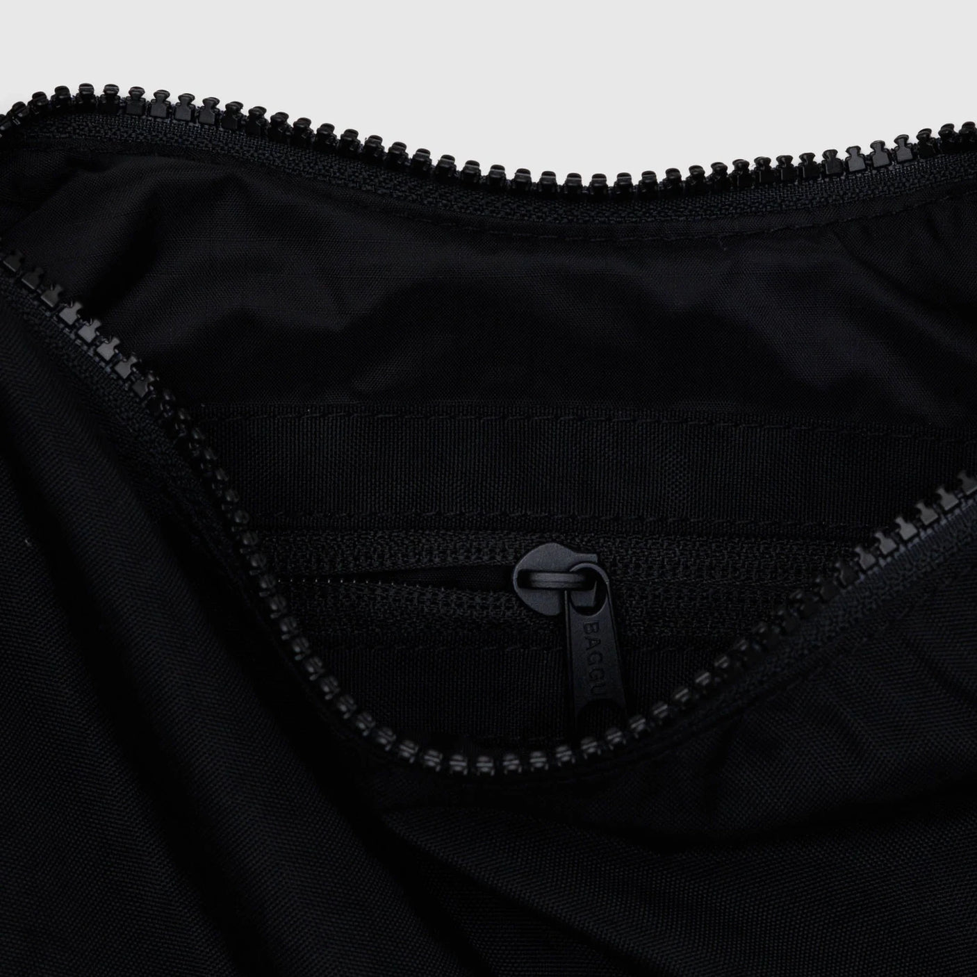 Black nylon crescent bag interior with zipper and stitched logo patch