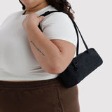 Small bowler bag in black worn crossbody with adjustable strap and zip top.
