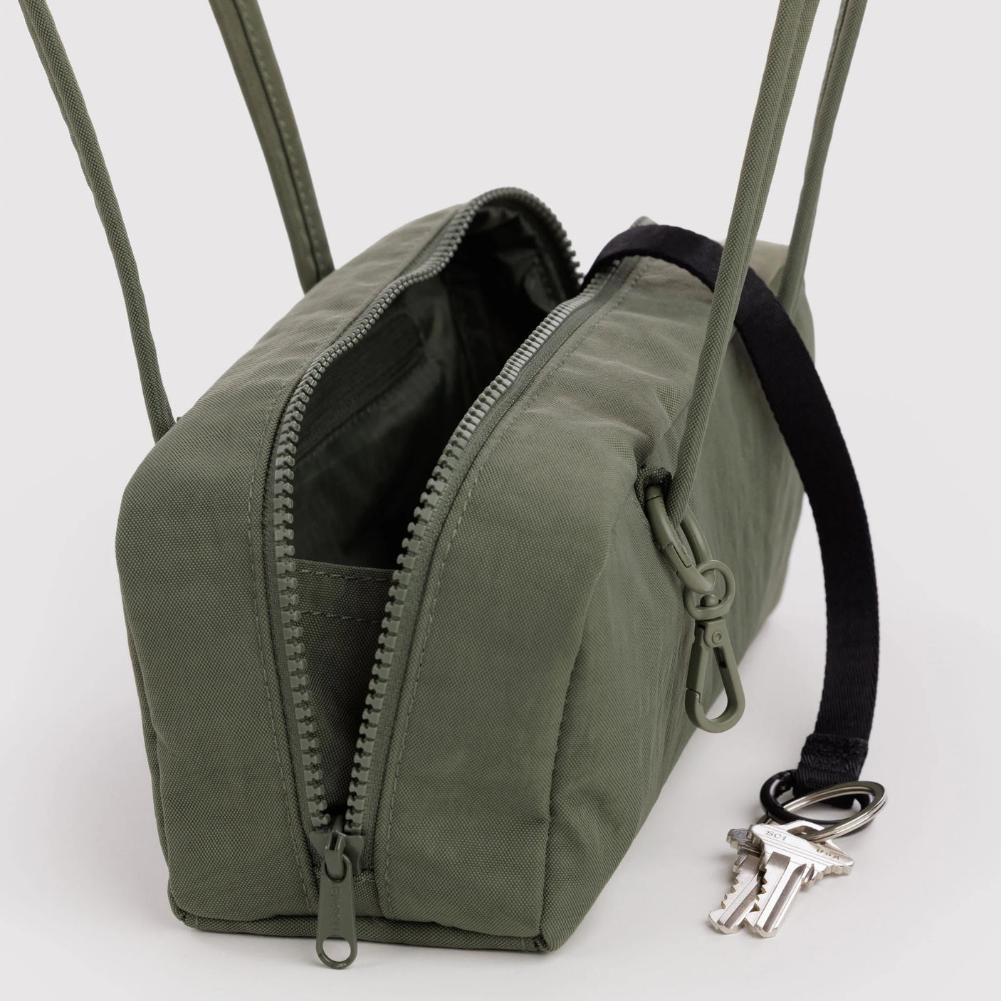 Olive small bowler bag with open zip, black-lined interior, and visible keys.