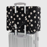 Polka-dot tote bag with cream dots, secured over a carry-on suitcase