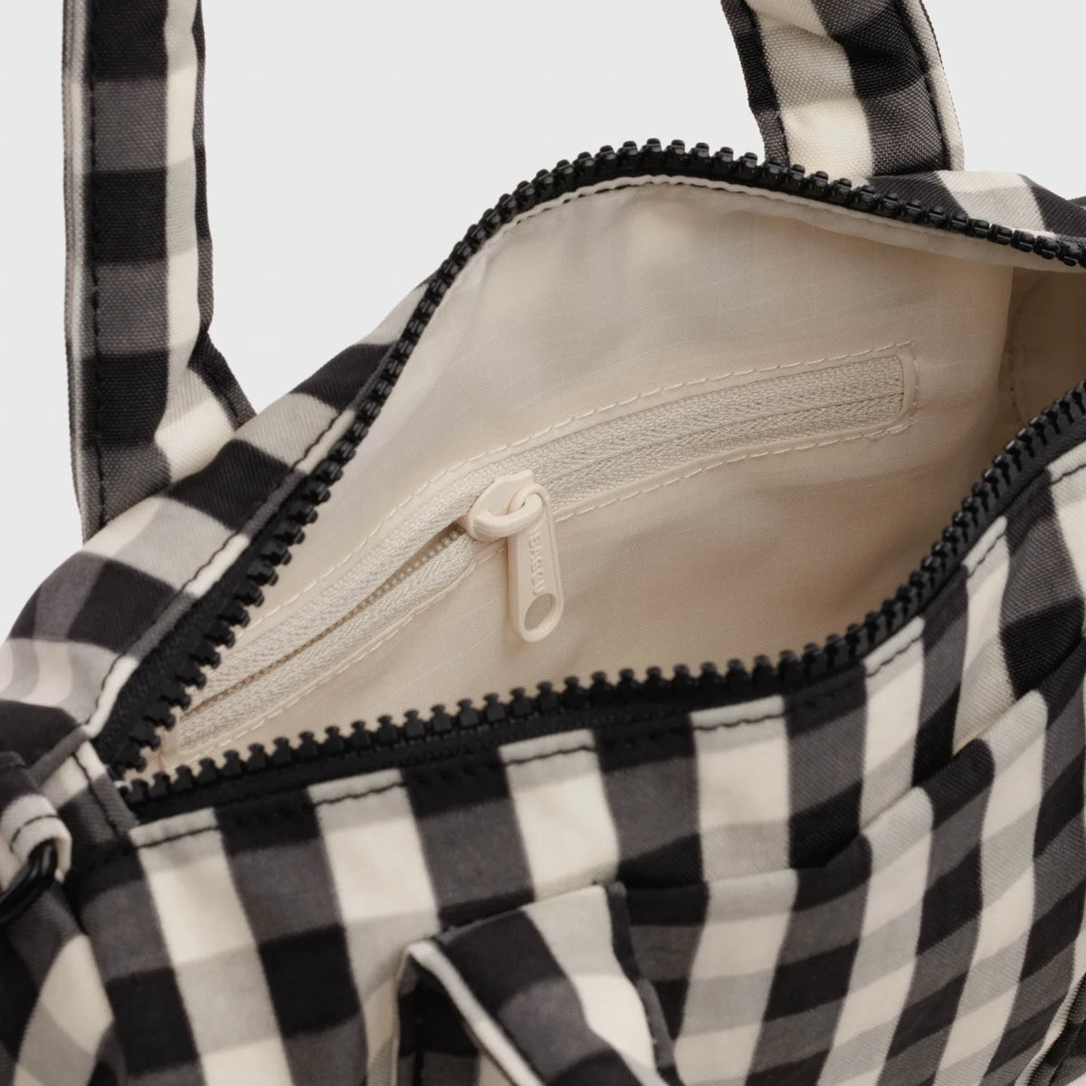 Duffel bag interior with zipper pocket and fabric lining, cream and black