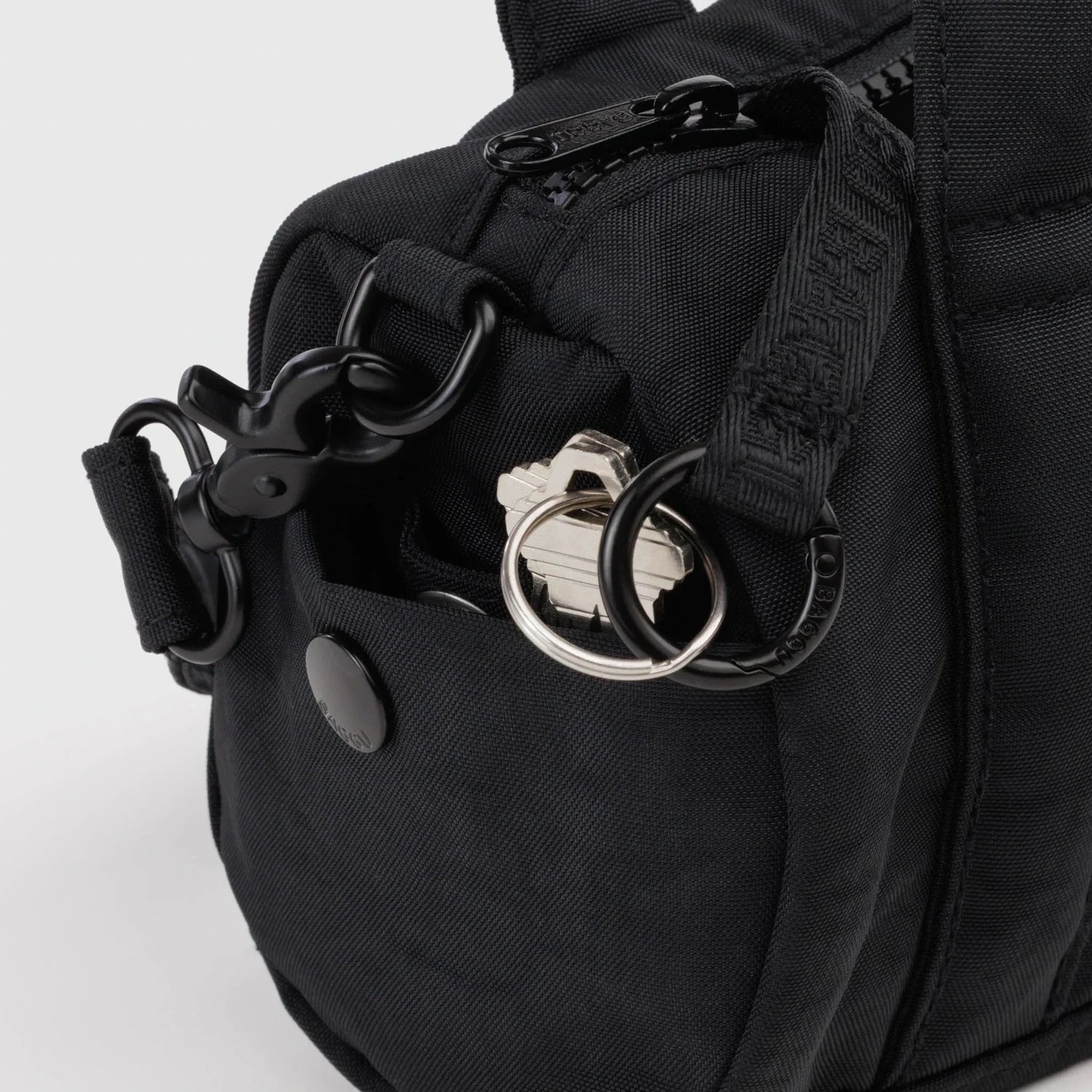 Black nylon duffle bag hardware detail with metal rings and strap clips