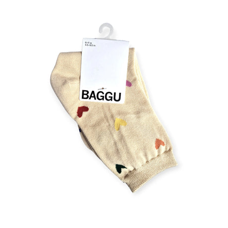 A pair of Baggu Crew Socks in beige featuring small embroidered colorful hearts, made from bamboo rayon and packaged in a white cardboard sleeve labeled "Baggu" with a hanging hook.