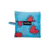 The Baggu Standard Bag - Keith Haring Hearts by Baggu is a reusable, foldable bag made from recycled nylon, showcasing a blue design with red hearts and black accents and equipped with a durable black strap.