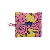 The Baggu Standard Reusable Bag, designed by Baggu, showcases a striking pink rose pattern set against a yellow backdrop, reflecting eco-conscious values with its reusable design.