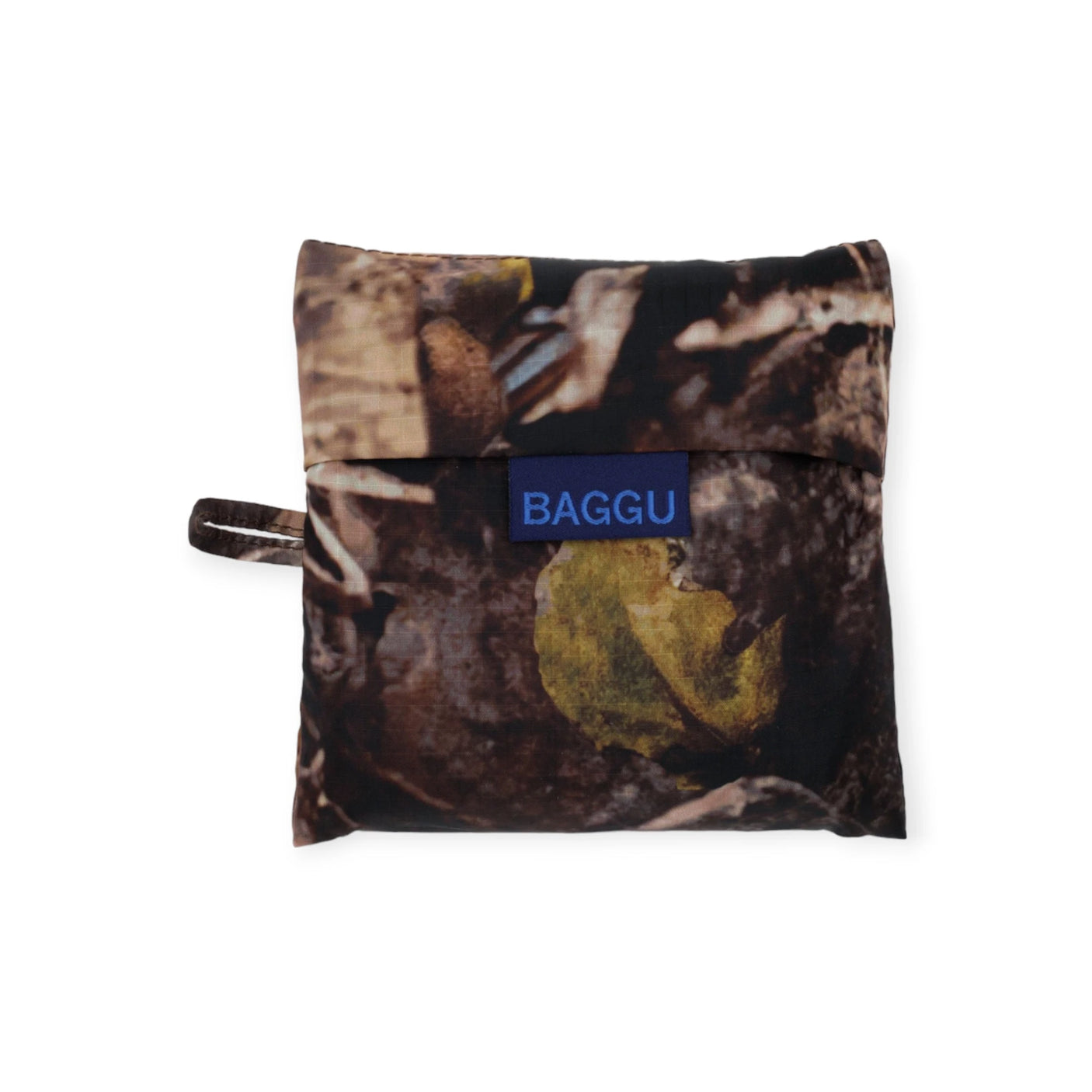 The Baggu Standard Reusable Bag - Photo Forest, made from recycled nylon in a camouflage design, includes a blue logo tag on the front for compact convenience.