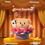 Plush bear popping from magician’s hat holding playing cards on stage with red and yellow striped curtains background