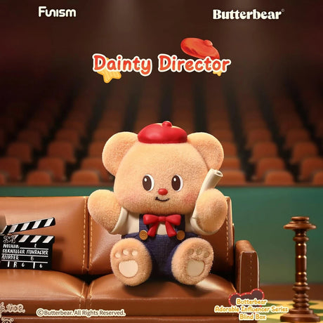 Plush bear wearing red beret and bow tie holding film script sitting on leather couch in theater setting