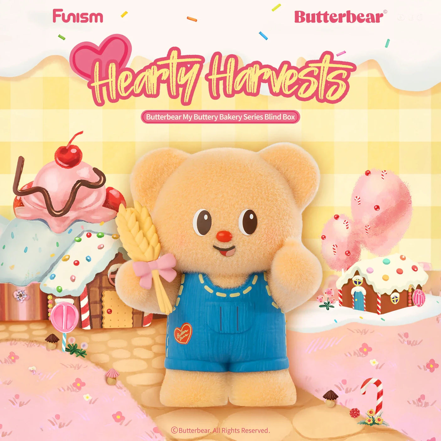 Light brown plush bear in blue overalls holding wheat stalk with pink bow in candy-coated bakery village background