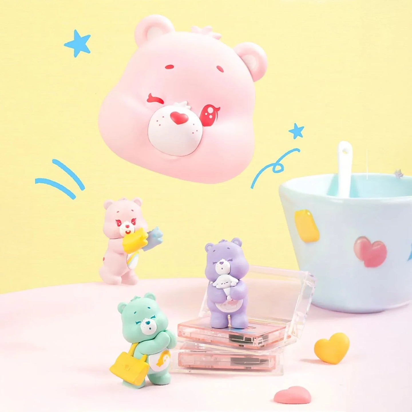 Pink bear carrying case with heart face, with four small bear mini figures beside it.