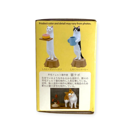 The Cat Bakery Waiter Blind Box by Kitan Club unveils delightful figurines: a white cat with a donut and a black-and-white cat with coffee, capturing a playful feline vibe. Japanese text below complements an adorable cat photo.