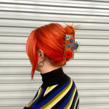 Flower claw clip on bright red hair bun with colorful daisy and red bloom