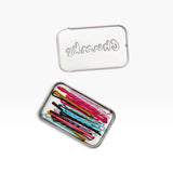Bobby pins in a small metal tin with lid; multicolor pins visible inside