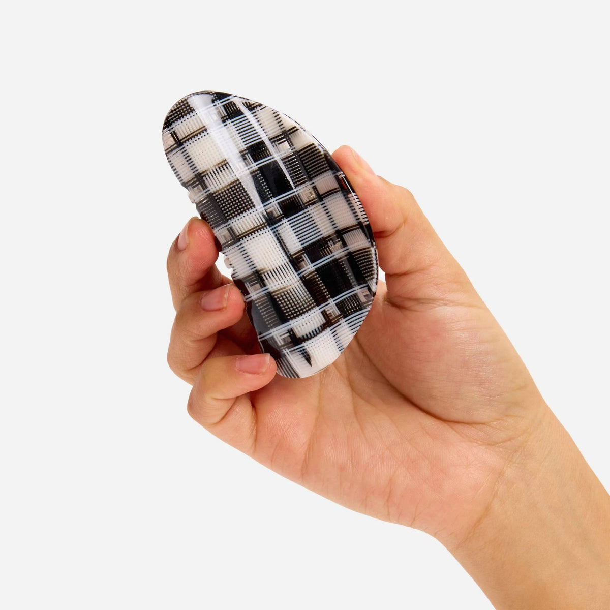 Black-and-white plaid claw clip held in hand, curved profile with teeth