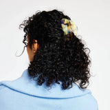 Curly hair secured with pastel translucent claw clip on the back