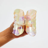 Pastel translucent acrylic claw clip shown open with central spring hinge