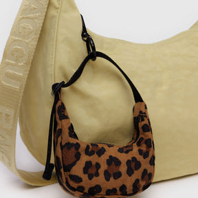 Leopard print Baggu Crescent Bag Charm attached to beige Baggu shoulder bag with branded strap on white background