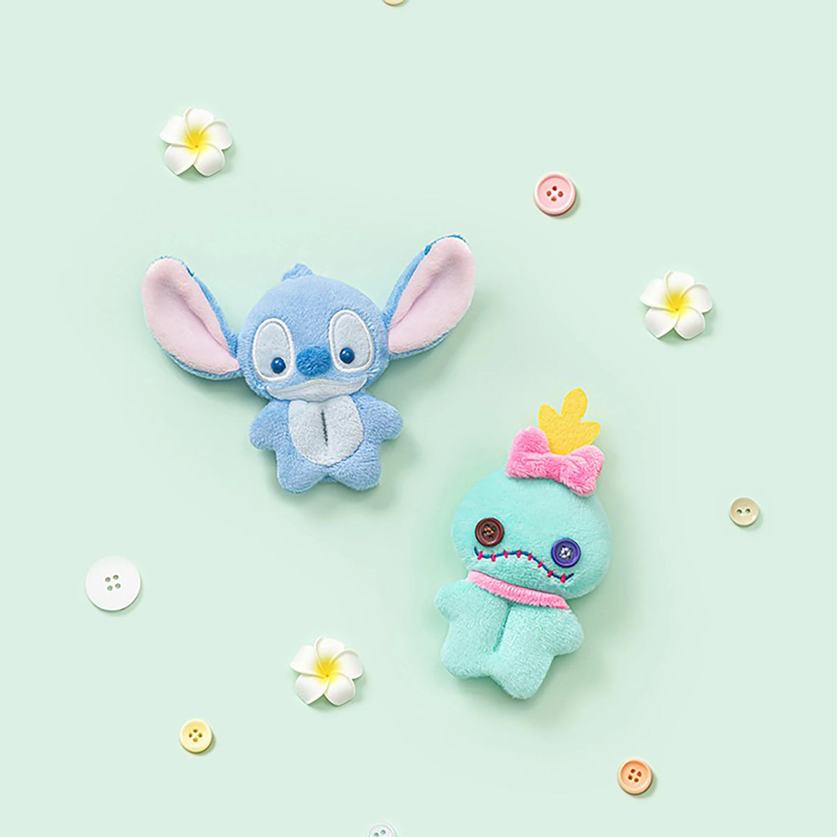Two small plush character charms, blue and teal, with button accents and embroidered faces.