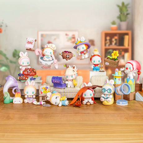 Lucky Emma’s Emma Fairy Babe Academy Blind Box figurines are displayed on a table and sofa in a cozy room with plants and shelves in the background.