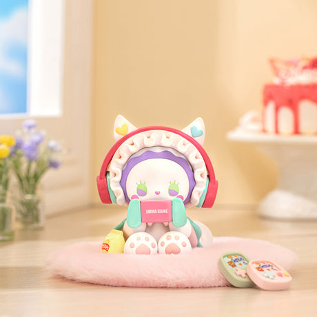 Small Emma Secret Forest Love Dopamine figure wearing large red headphones and holding a pink gaming console on soft pink cushion