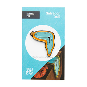 Enamel pin depicting Dali’s melting clock from Persistence of Memory on blue backing card, gallery image 1.webp