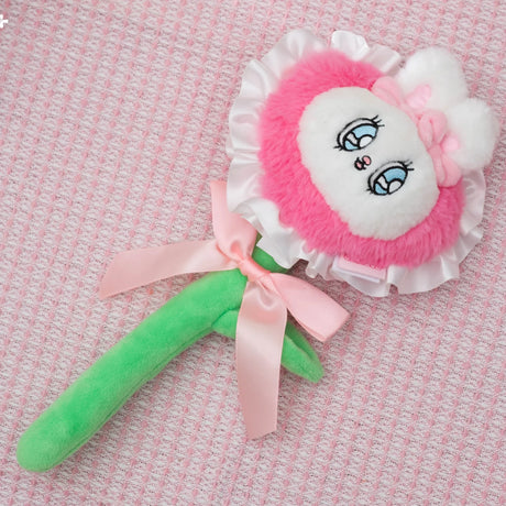 Pink and white Esther Bunny flower plush with green stem and satin bow on textured pale pink fabric background