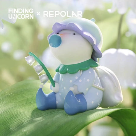 Finding Unicorn REPOLAR Magical Garden figure dressed in blue with a flower hat holding a lily of the valley outdoors
