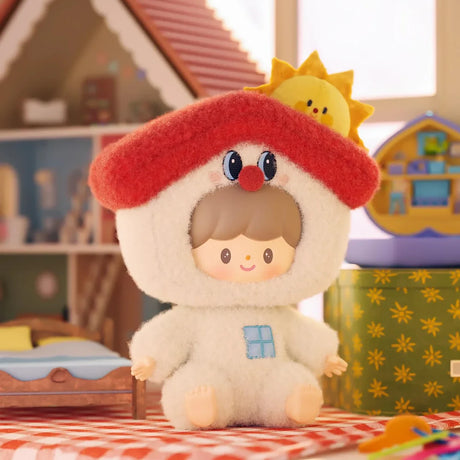 Small plush keychain figure dressed in a cozy white outfit with a red roof hat and smiling sun accessory behind