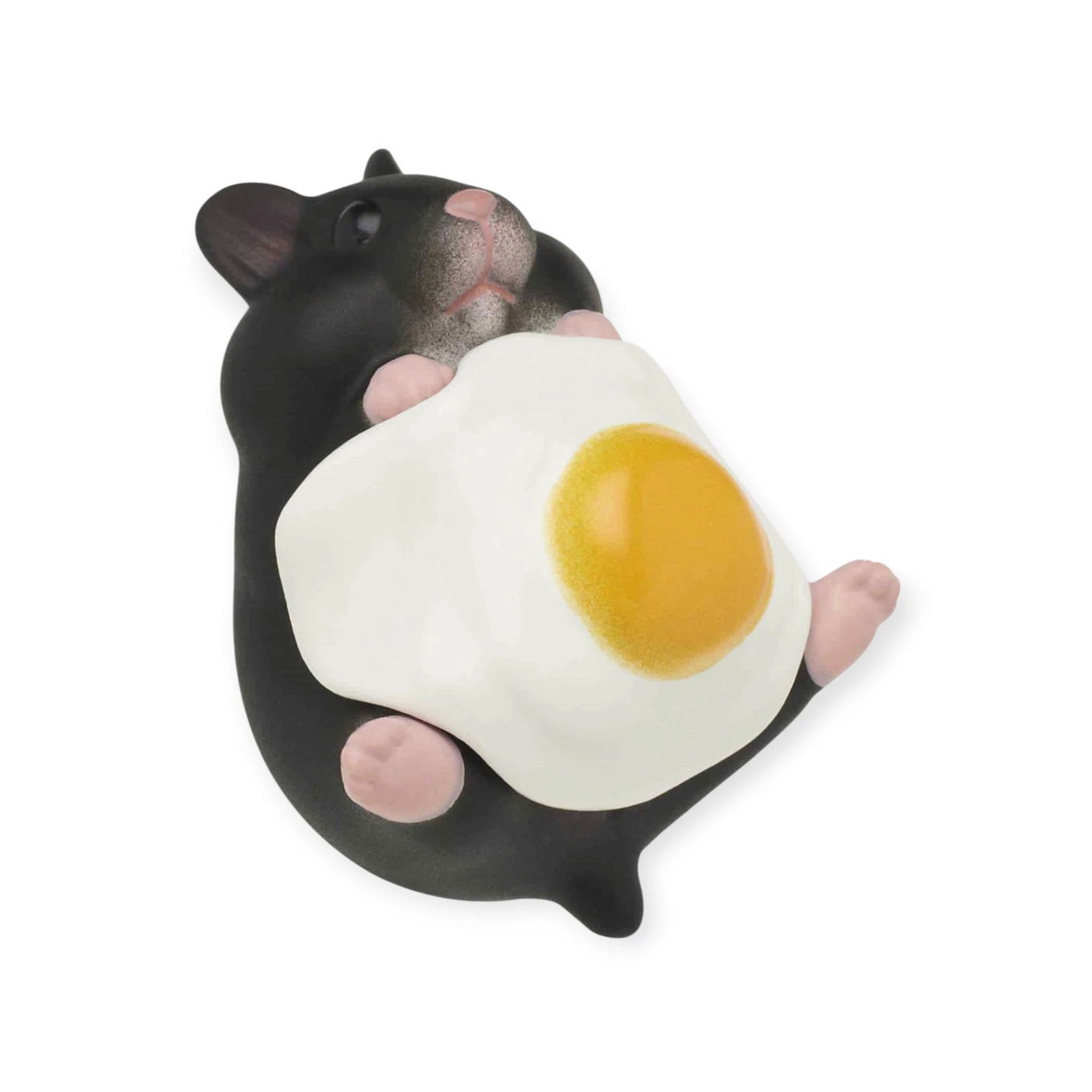 A small, black and white figure resembling a hamster from Kitan Club's Hamster 'N Egg Blind Box is holding an egg-shaped object with a yellow center.