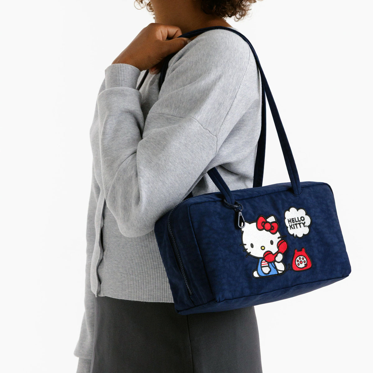 Navy Hello Kitty nylon bowler bag with top handles, worn on shoulder