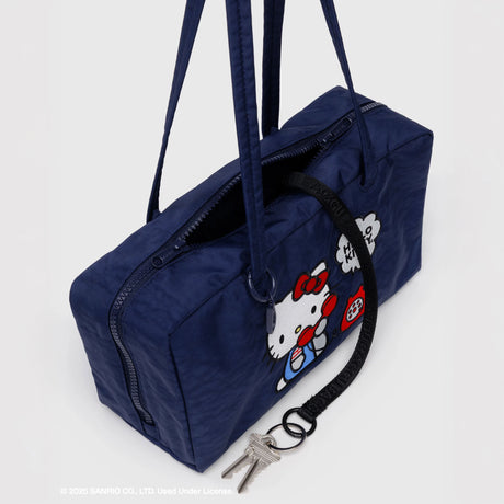 Overhead view of navy Hello Kitty x Baggu Nylon Bowler Bag with keychain and Hello Kitty graphic, promo image 4