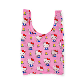 The Standard Baggu - Hello Kitty - Pink by Baggu features a repeating Hello Kitty pattern with her holding a yellow flower, displayed on a pink reusable bag against a white background.